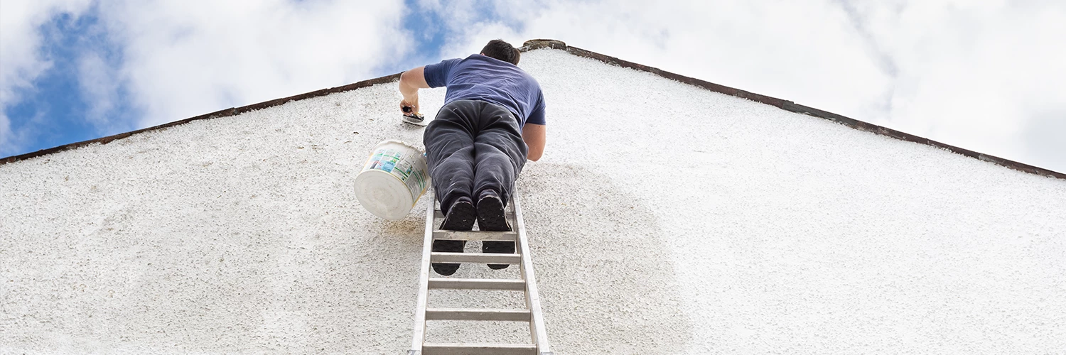 man on ladder painting house exterior