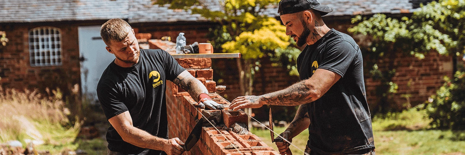 two bricklayers building a wall
